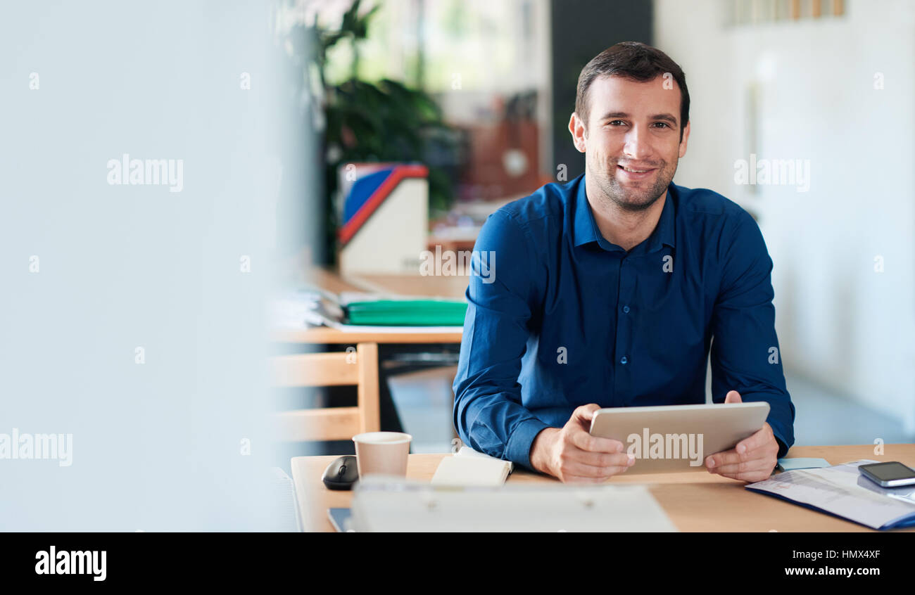 Smiling businessman using a digital tablet in an office Banque D'Images