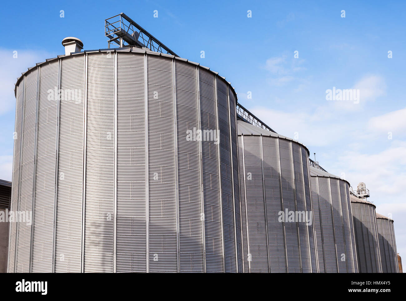 Silos agricoles. Extérieur du bâtiment. L'entreposage et le séchage de céréales, blé, maïs, soja, tournesol contre le ciel bleu avec des nuages blancs Banque D'Images