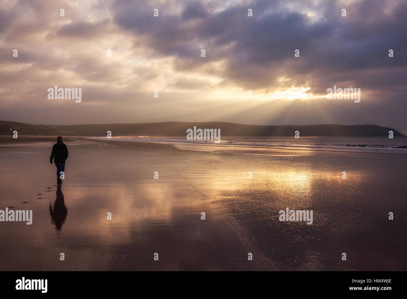 Silhouette femme marche seul sur la plage de Woolacombe Sands dans le Nord du Devon, England, UK Banque D'Images