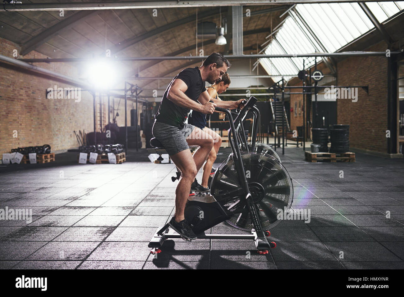 Vue latérale des jeunes en séance de sport et d'équitation, vélo sur les machines de grande salle de sport moderne. Banque D'Images