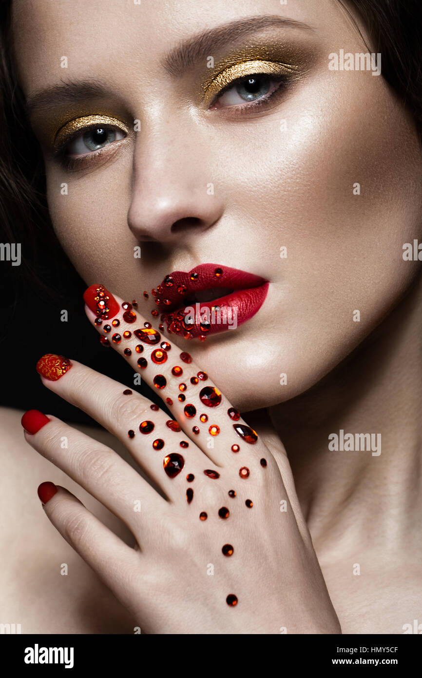 Belle fille avec soir maquillage, lèvres rouge en strass et clous. manucure design beauté visage. Banque D'Images