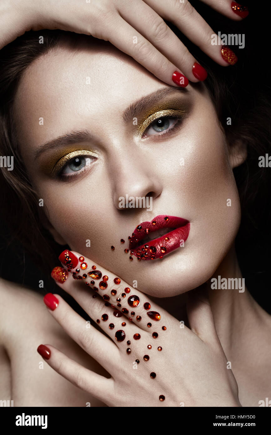Belle fille avec soir maquillage, lèvres rouge en strass et clous. manucure design beauté visage. Banque D'Images