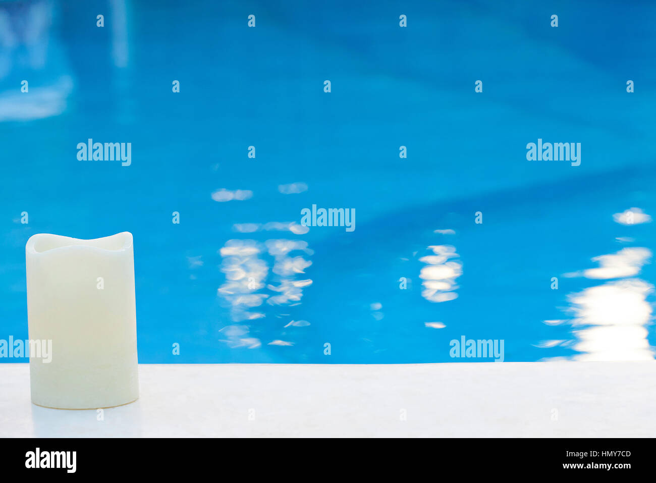 Close up of bougie blanche sur fond bleu, piscine extérieure avec de l'eau bleue Banque D'Images