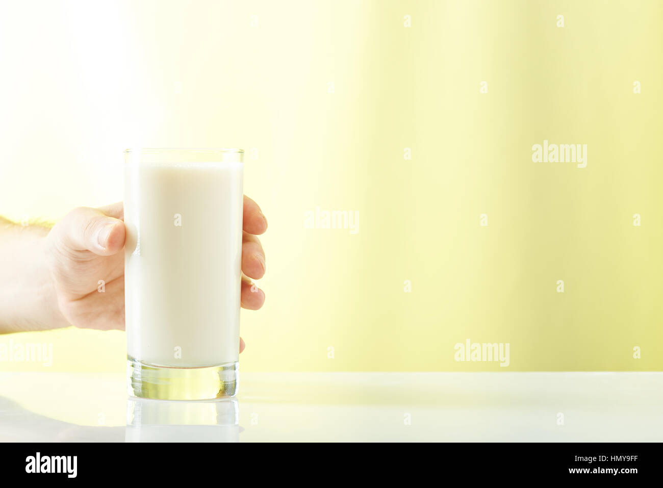 Prendre la main verre de lait isolé sur fond jaune Banque D'Images