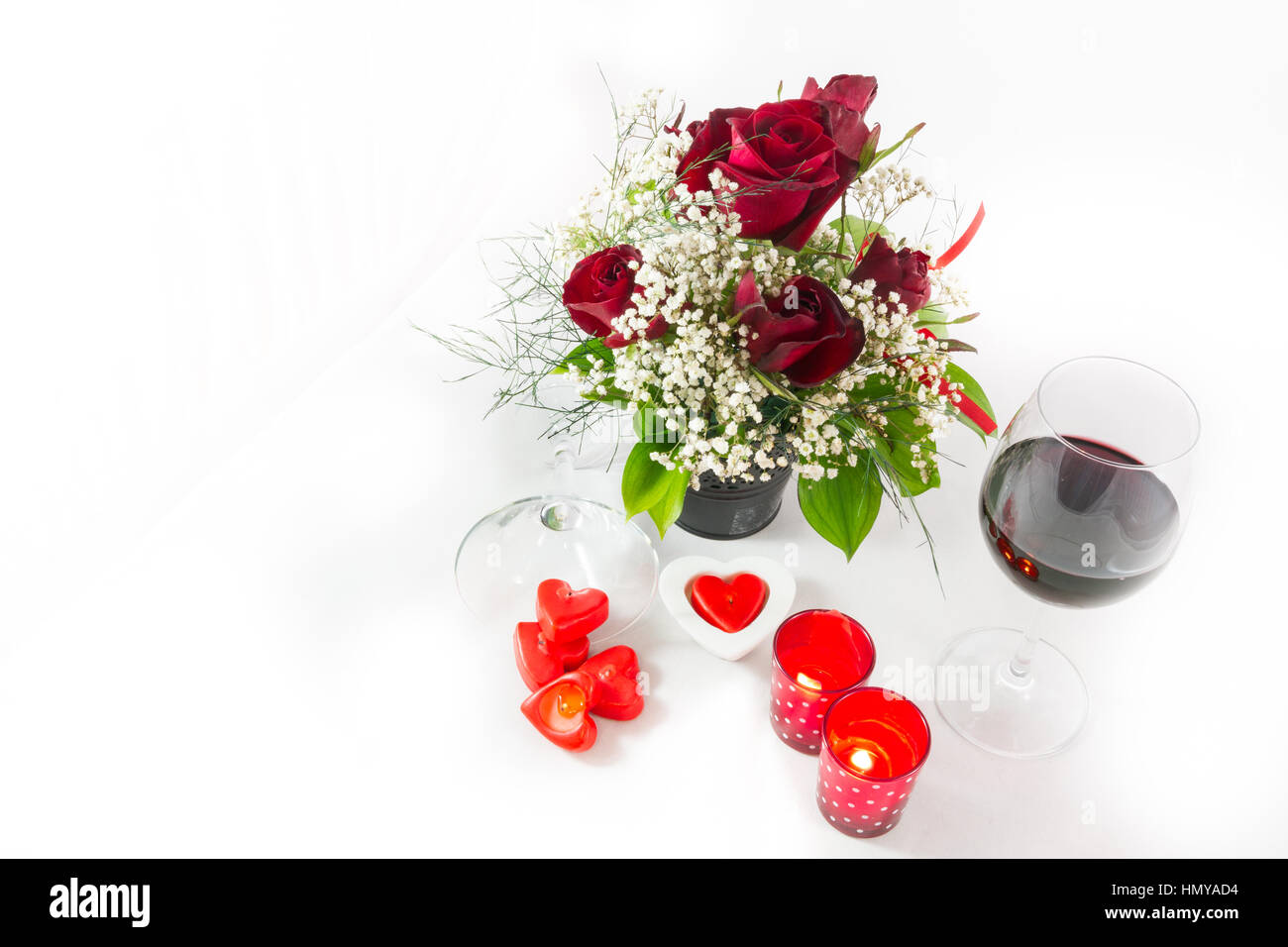 Composition d'un bouquet de roses Valentines Day et vin rouge en forme de coeur bougies sur fond blanc- vue supérieure gauche avec copyspace Banque D'Images