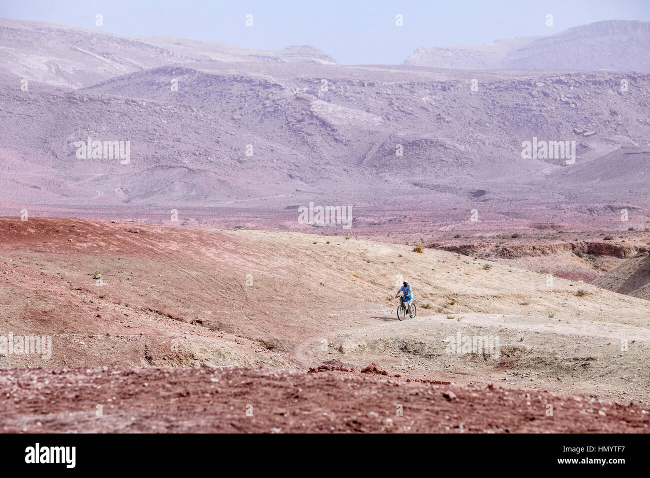 Le Maroc. Man Riding Bicycle près de Ksar Ait Benhaddou, un site du patrimoine mondial. Banque D'Images