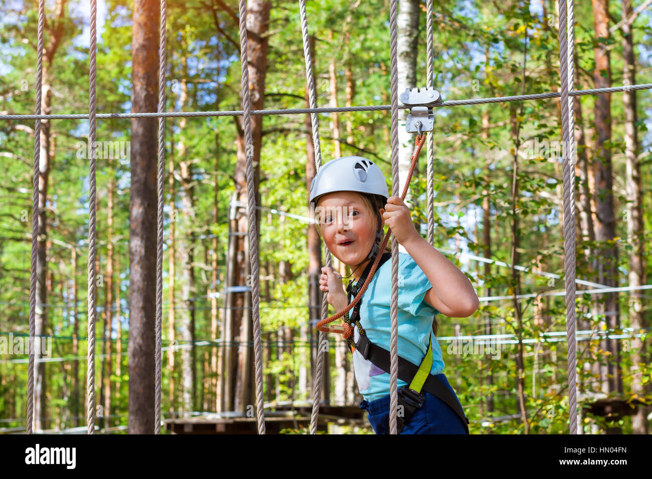 Adolescente poursuit en sentier à charnière dans l'extrême parc en forêt de l'été. L'escalade de haute altitude de la formation sur l'enfant parcours aventure, équipé de sa Banque D'Images