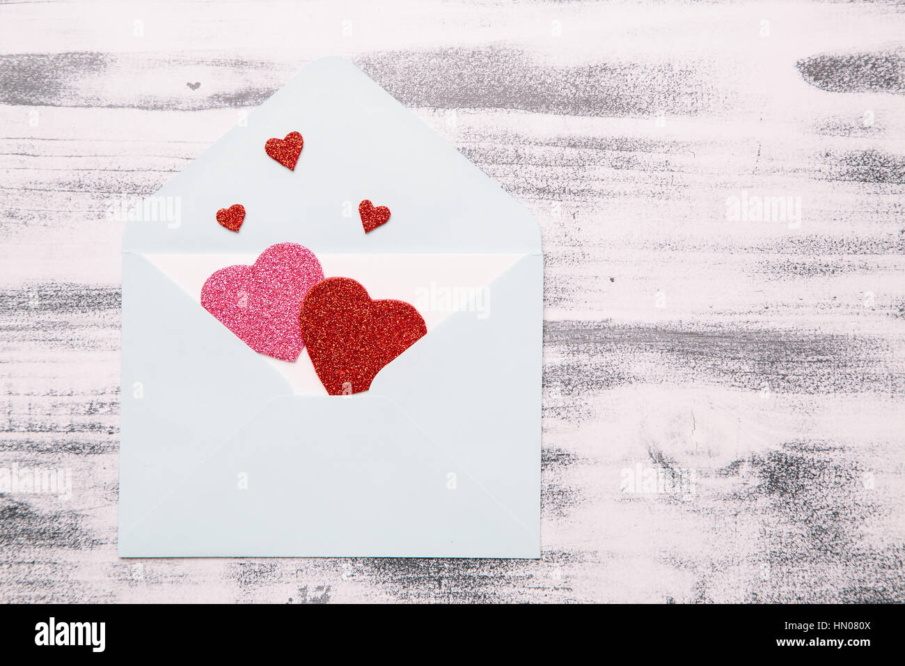 Enveloppe ouverte et red glitter hearts sur le fond blanc en bois miteux. Mise à plat. Concept de la Saint-Valentin, l'espace de copie, vue du dessus Banque D'Images