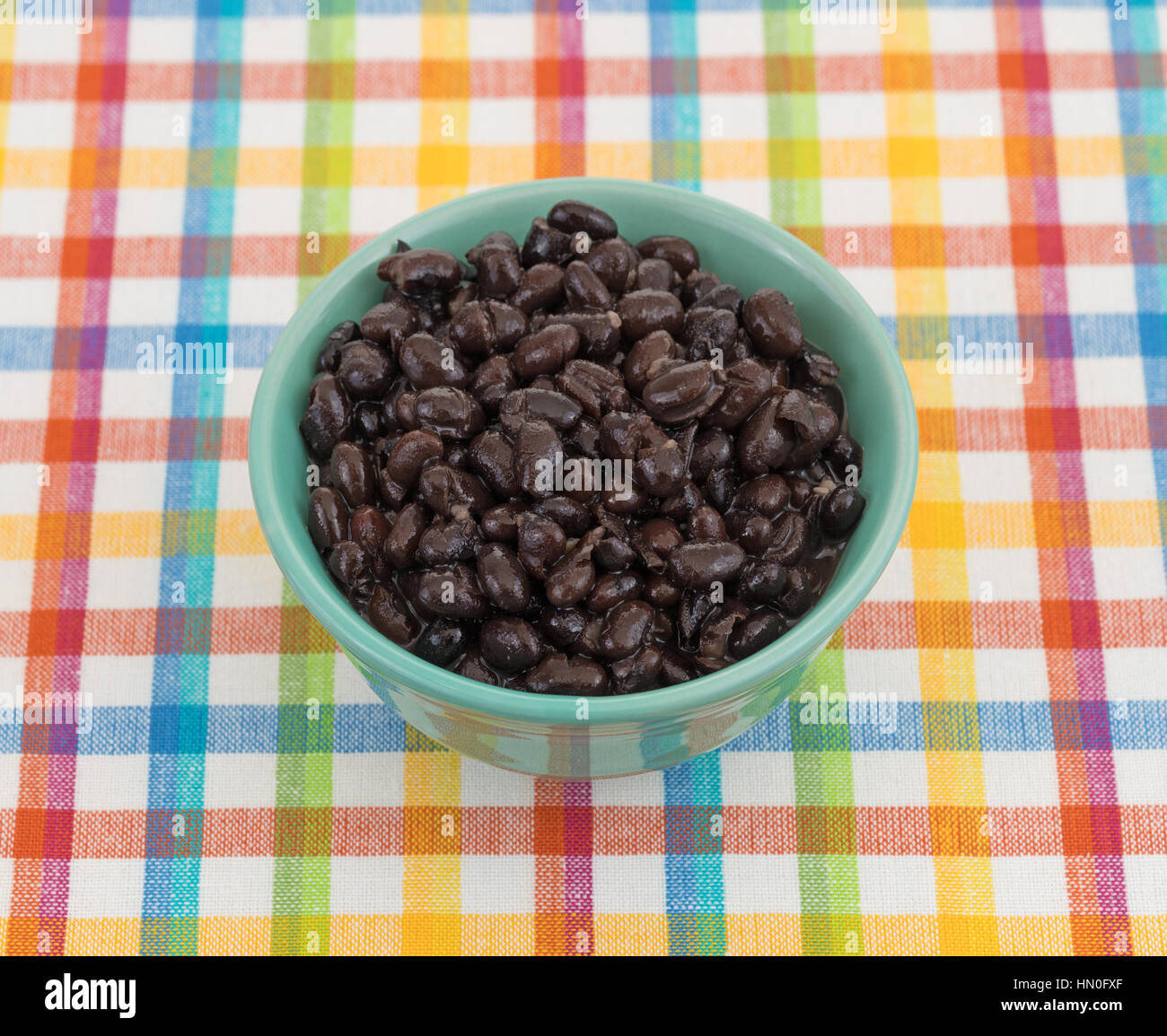 Une assiette de haricots noirs bio dans un bol sur un tapis coloré. Banque D'Images