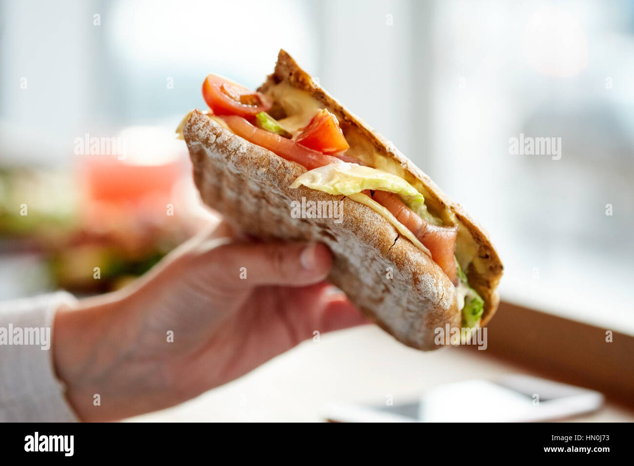 La main avec salmon sandwich panini au restaurant Banque D'Images