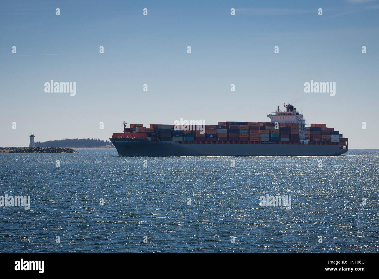 Un porte-conteneurs passe le phare à l'entrée du port de Halifax, Nouvelle-Écosse, Canada. Banque D'Images