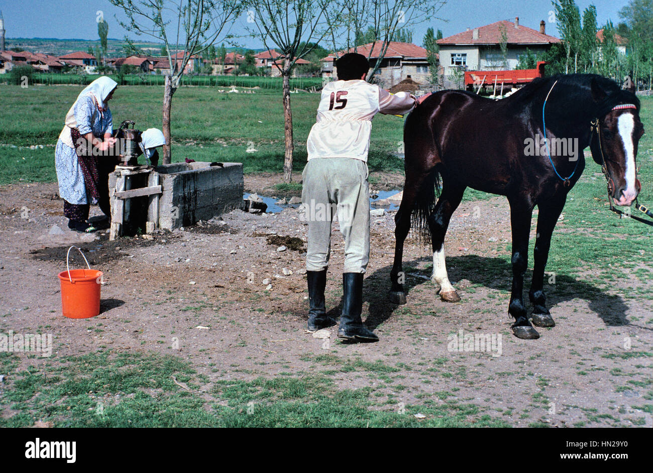La femme au puits et d'un cavalier turc palefreniers son cheval après une Jirit ou Cirit Jerred, jeu, une sorte de cheval ou concours de joutes, un sport lié à Polo, Turquie Banque D'Images