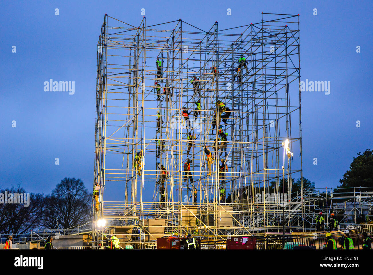 Image graphique des ouvriers grimpant alors qu'ils sont en train de démanteler des échafaudages sur pied libre à Twilight Banque D'Images