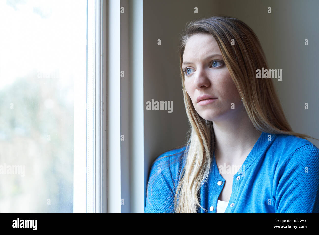 Femme triste souffrant de dépression à la fenêtre de Banque D'Images