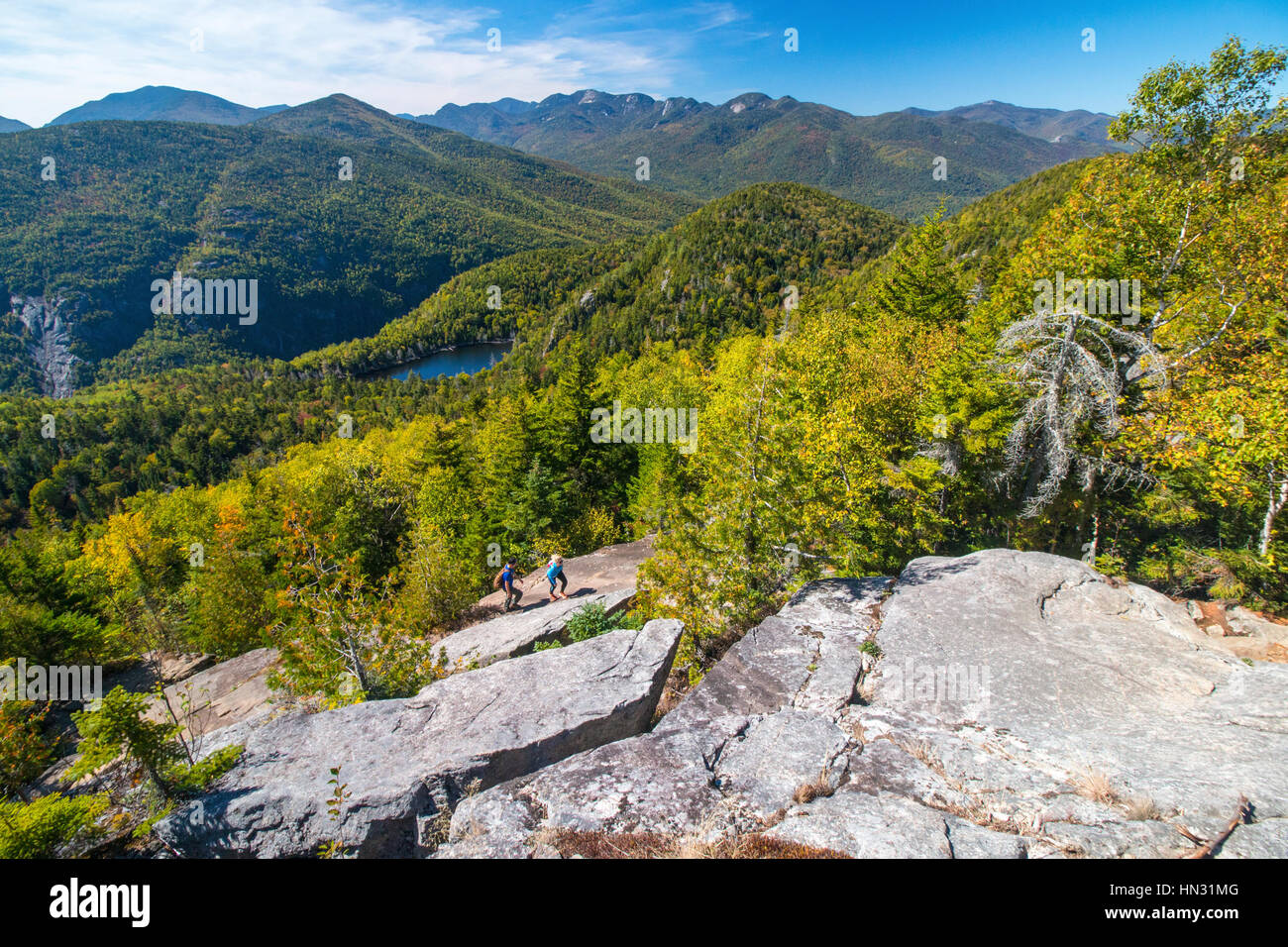 Jeune couple grimper dans la pente rocheuse donnant sur New England's Adirondack Park à l'automne, l'état de New York, USA Banque D'Images