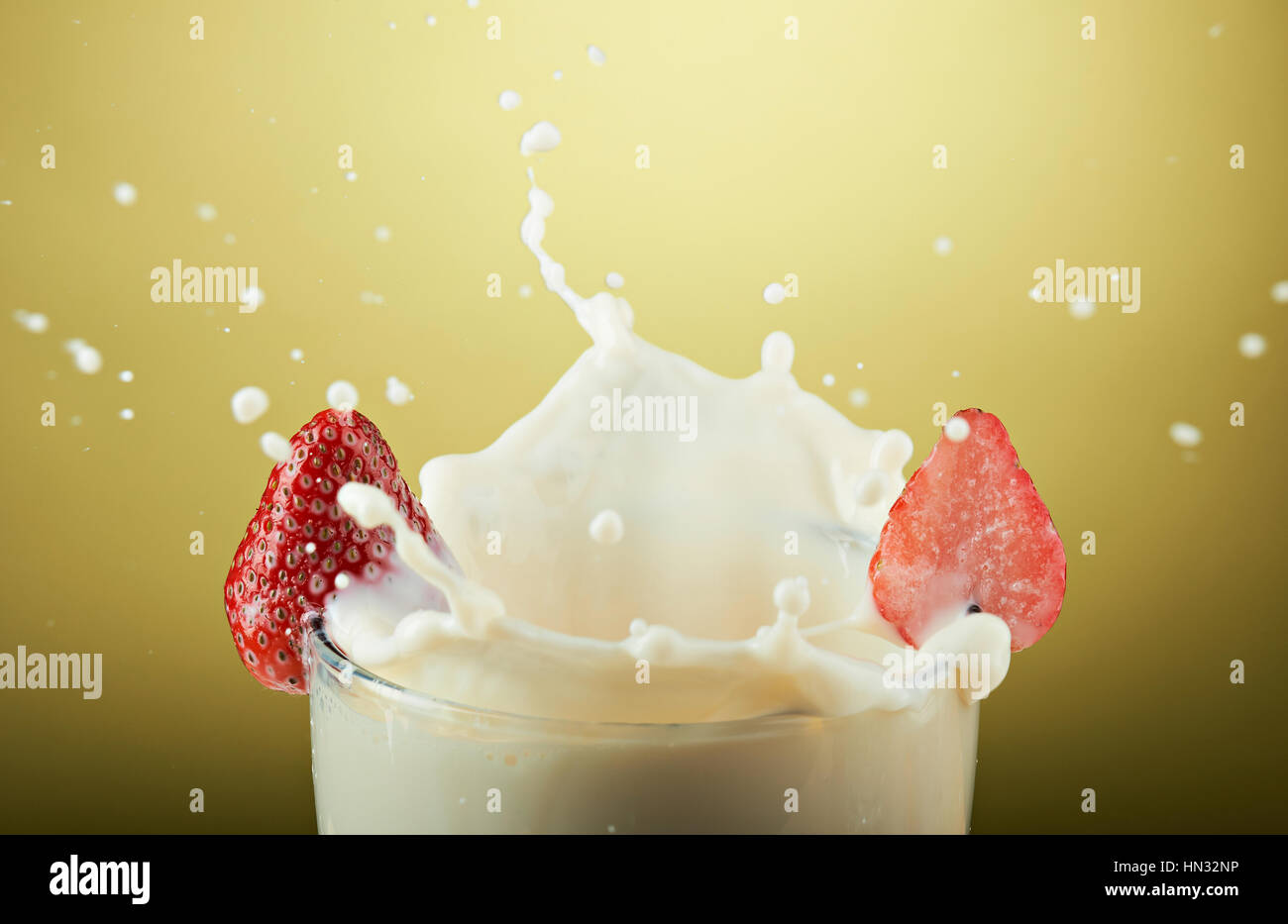 Big Splash de lait en verre isolé sur fond jaune Banque D'Images