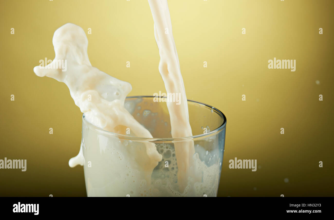 Verser le lait dans le verre close up isolé sur le jaune Banque D'Images