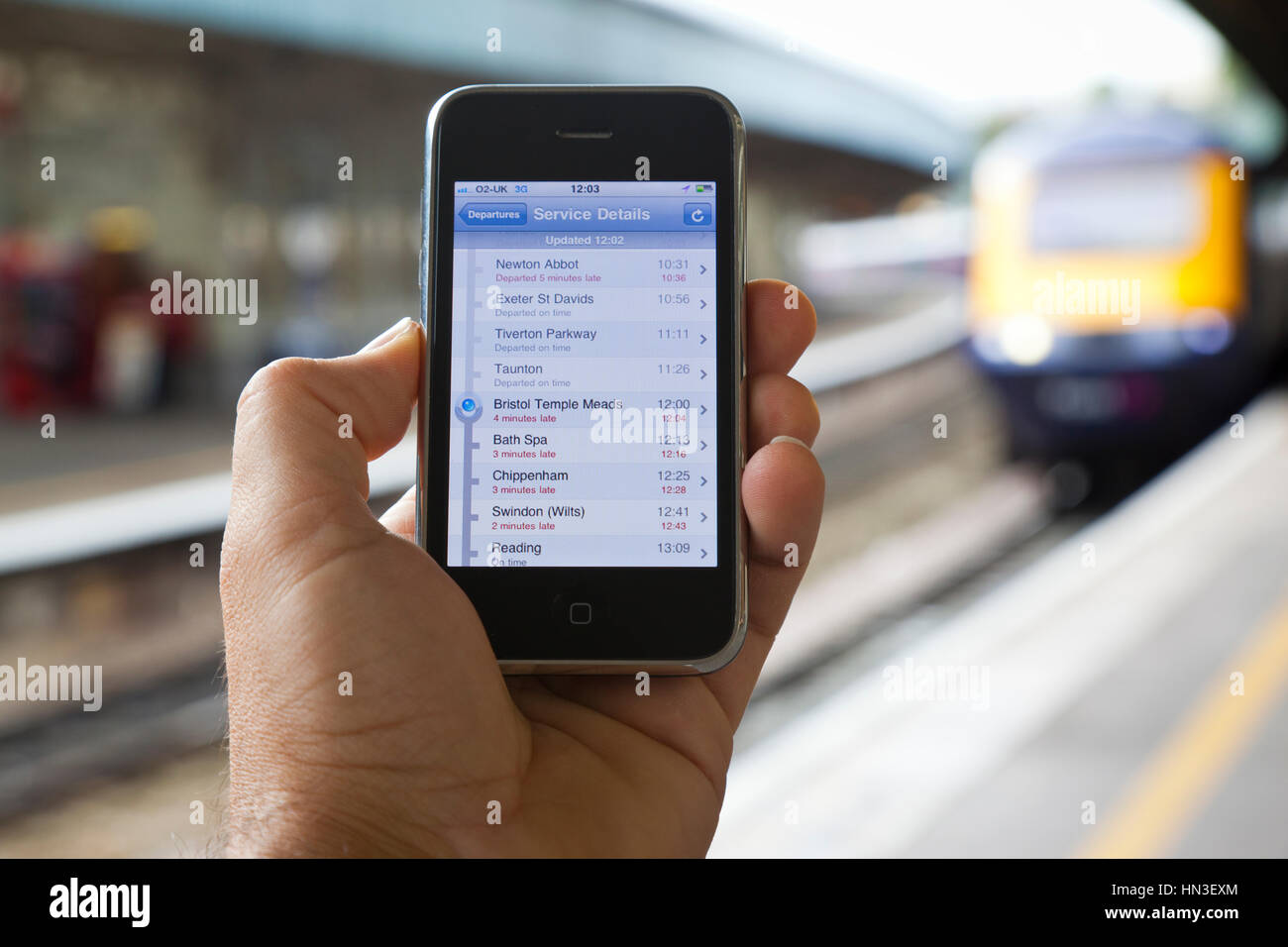 Bristol, Royaume-Uni - Octobre 4, 2011 : un mâle main tenant un identifiant Apple iPhone 3GS à la gare Temple Meads de Bristol avec l'arrivée d'une locomotive o Banque D'Images