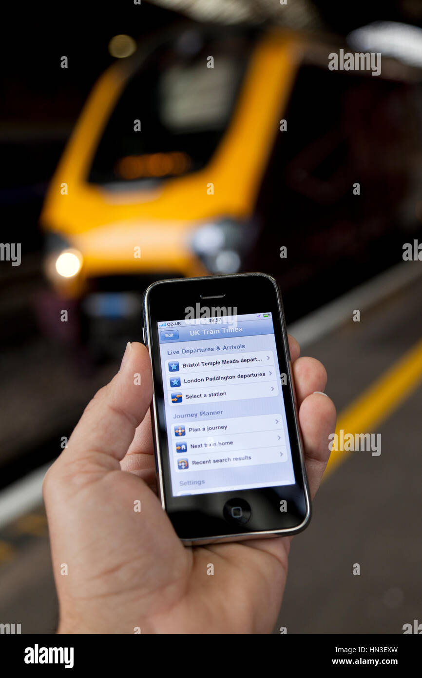 Bristol, Royaume-Uni - Octobre 4, 2011 : un mâle main tenant un identifiant Apple iPhone 3GS à la gare Temple Meads de Bristol avec un train de se concentrer dans le Banque D'Images