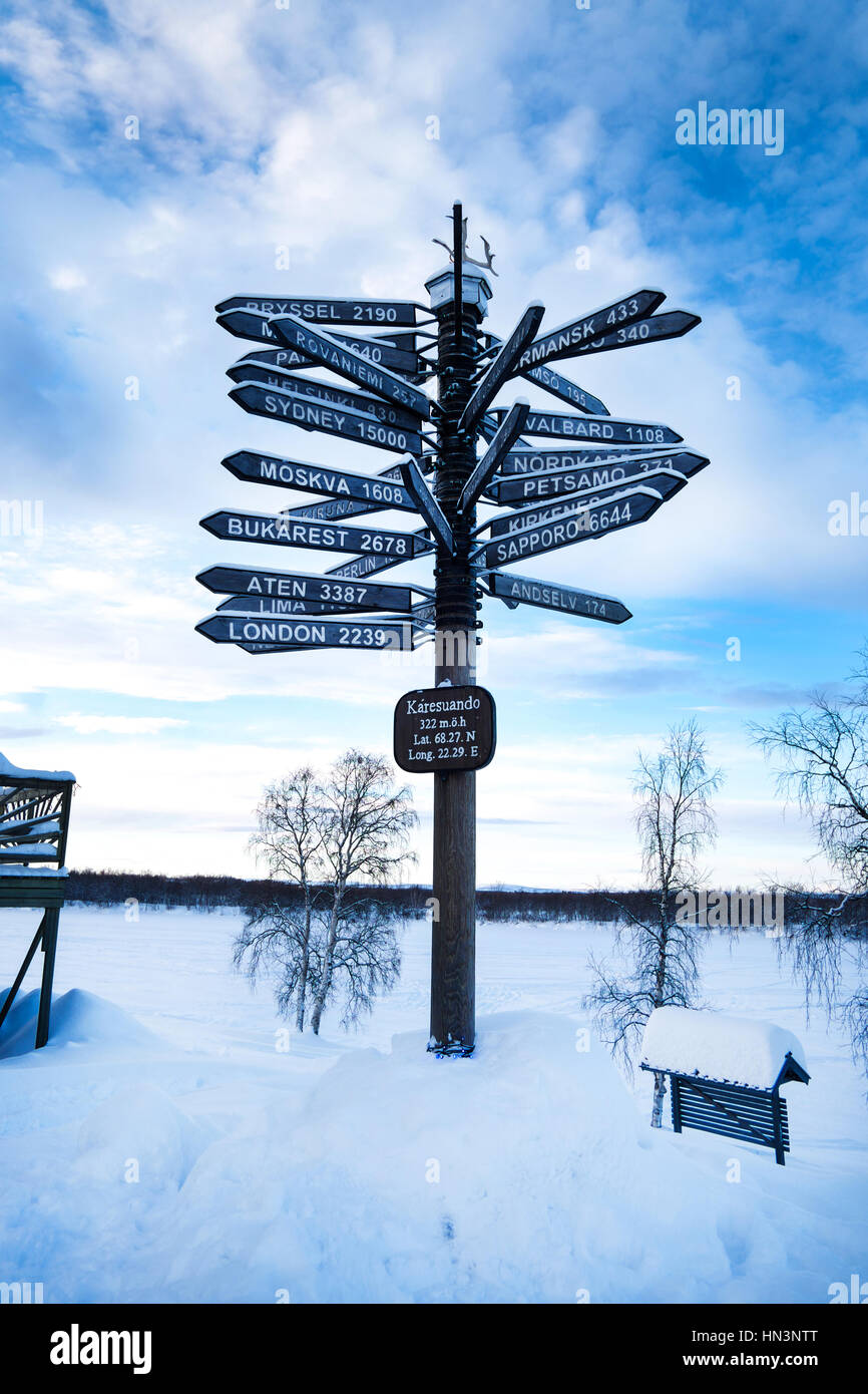 Panneau routier vers plus de 20 villes dans le monde, la neige au sol, ciel bleu, cercle arctique Banque D'Images