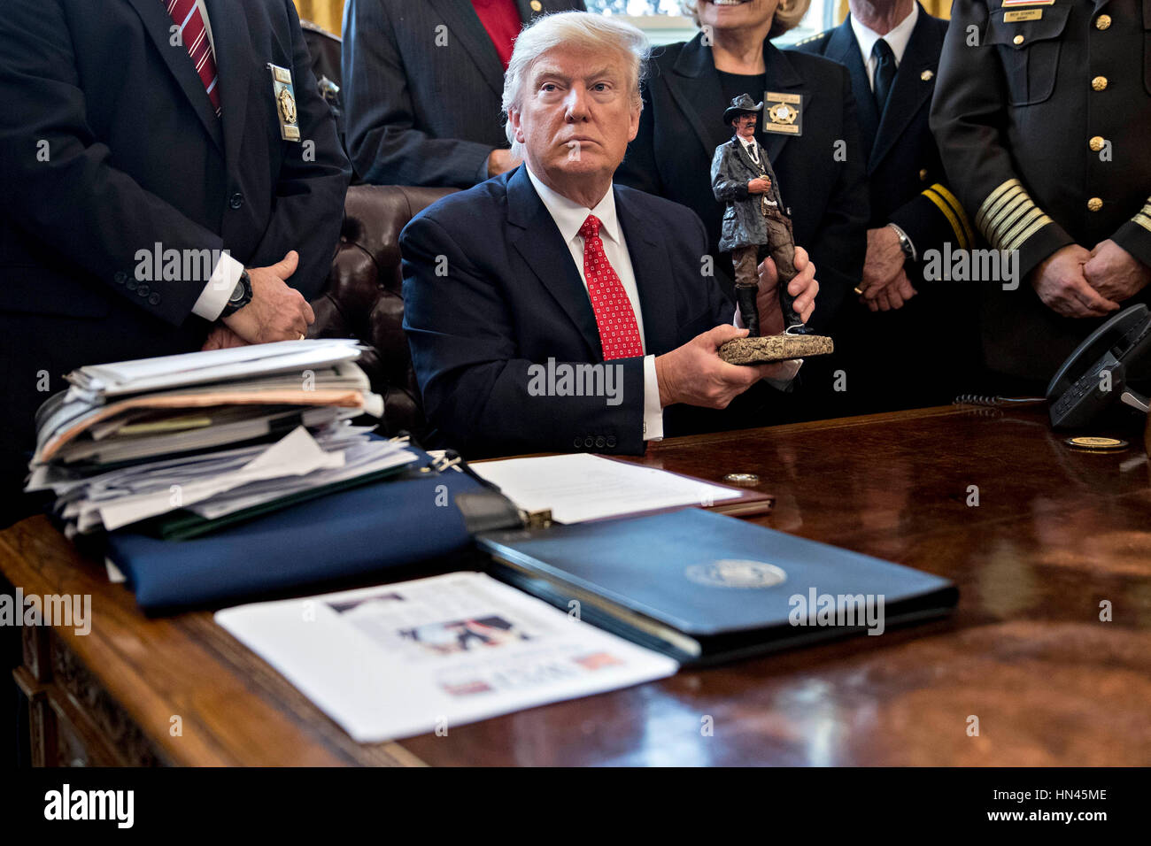 Le Président américain Donald Trump soutient une statue qu'il a reçu en cadeau lors de sa rencontre avec county sheriffs dans le bureau ovale de la Maison Blanche à Washington, DC, États-Unis, le mardi, 7 février 2017. L'administration d'Atout sera de retour en cour mardi pour faire valoir qu'il a une grande autorité sur la sécurité nationale et d'exiger le rétablissement d'une interdiction de voyager à sept pays à majorité musulmane que les réfugiés en détresse, a déclenché des protestations et remis le jeune gouvernement son premier test crucial. Crédit : Andrew Harrer/Piscine via CNP - PAS DE SERVICE DE FIL- Photo : Andrew Harrer/consolidé/Piscine/dpa Banque D'Images