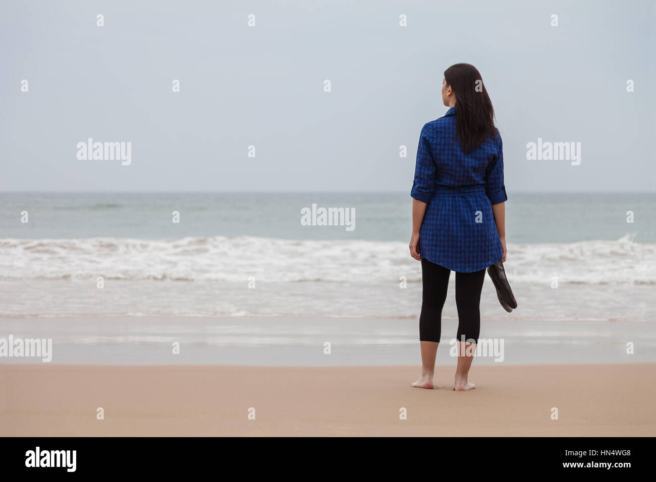 Femme solitaire et déprimée debout en face de la mer dans une plage déserte un jour d'automne / femme plage seule solitaire triste tristesse déprimée Banque D'Images
