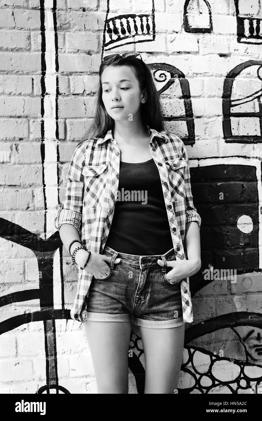 Portrait of teenage girl portée sur la chemise à carreaux et jeans shorts, contre un mur avec un certain élément de graffitis. Banque D'Images