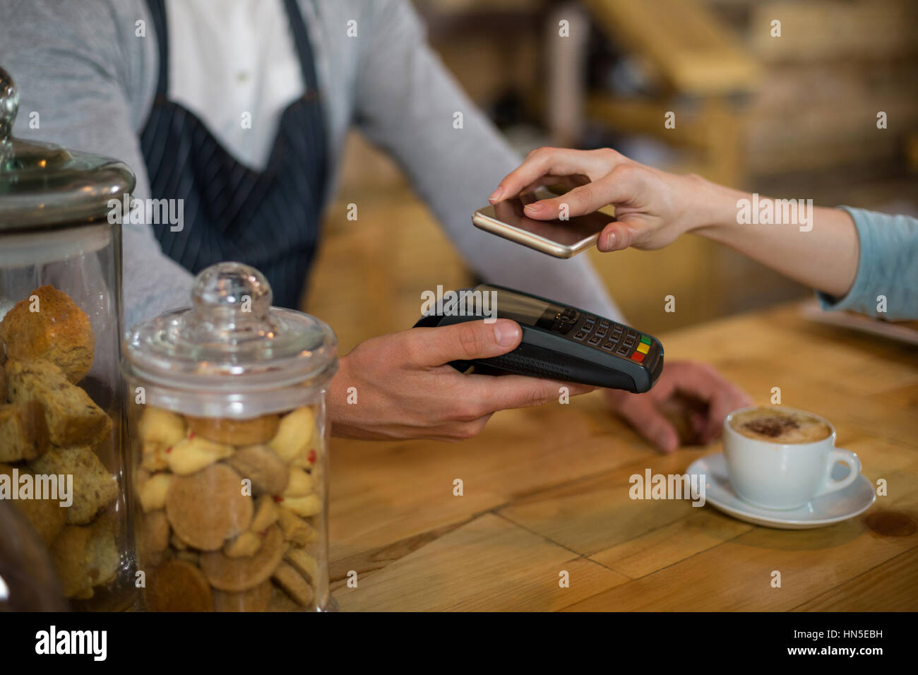 Femme de payer bill par smartphone à l'aide de la technologie NFC dans cafe Banque D'Images