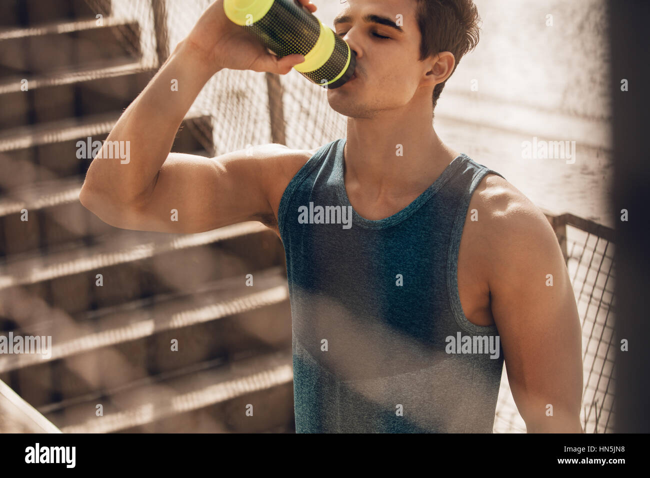 Coup de jeune homme musclé par l'eau potable la plage après l'entraînement. L'eau potable Runner après l'exercice et de prendre congé. Banque D'Images