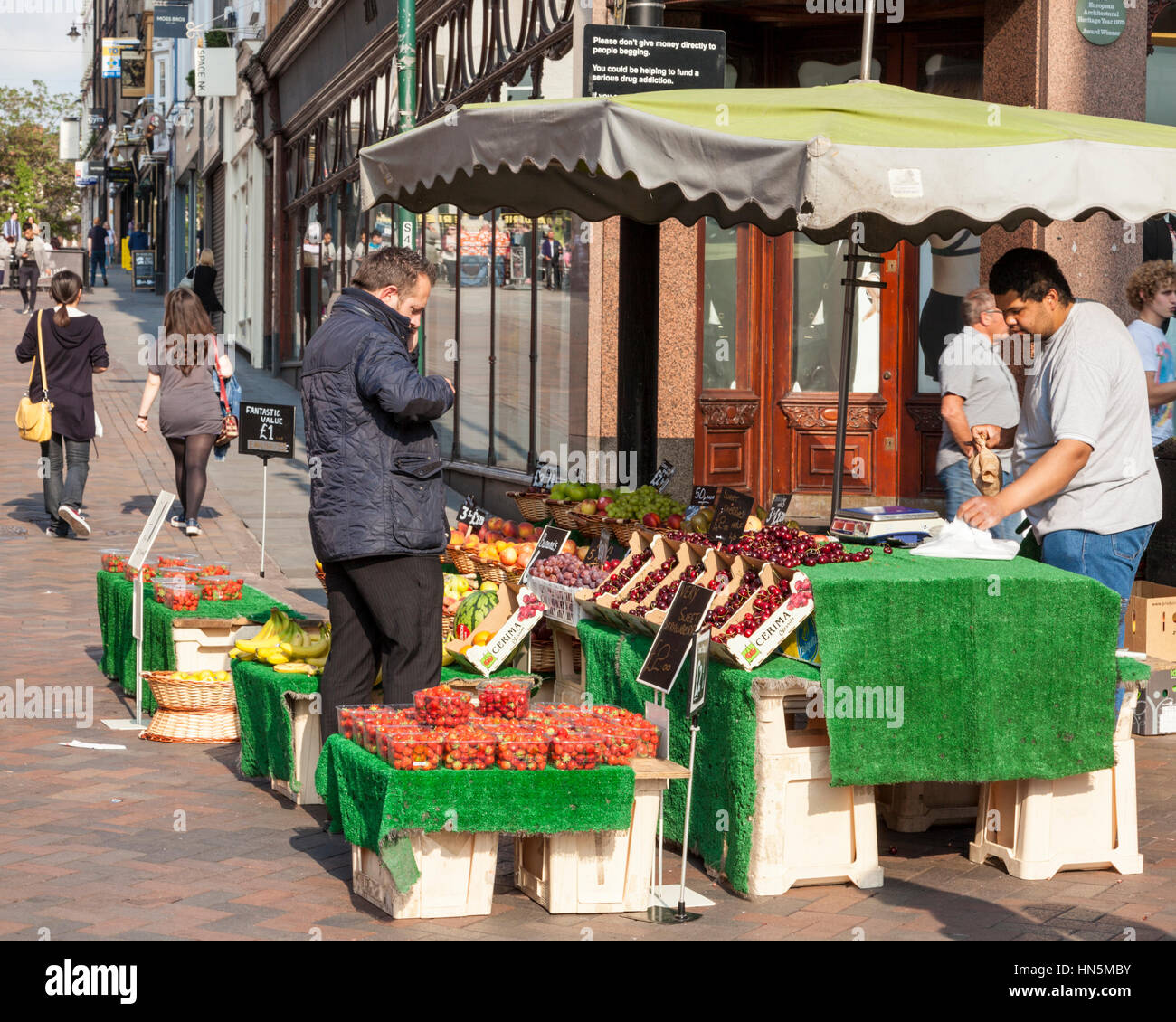 Vendeur de fruits. Opérateur de marché vendant des fruits à un client à son échoppe à Nottingham, Angleterre, Royaume-Uni Banque D'Images