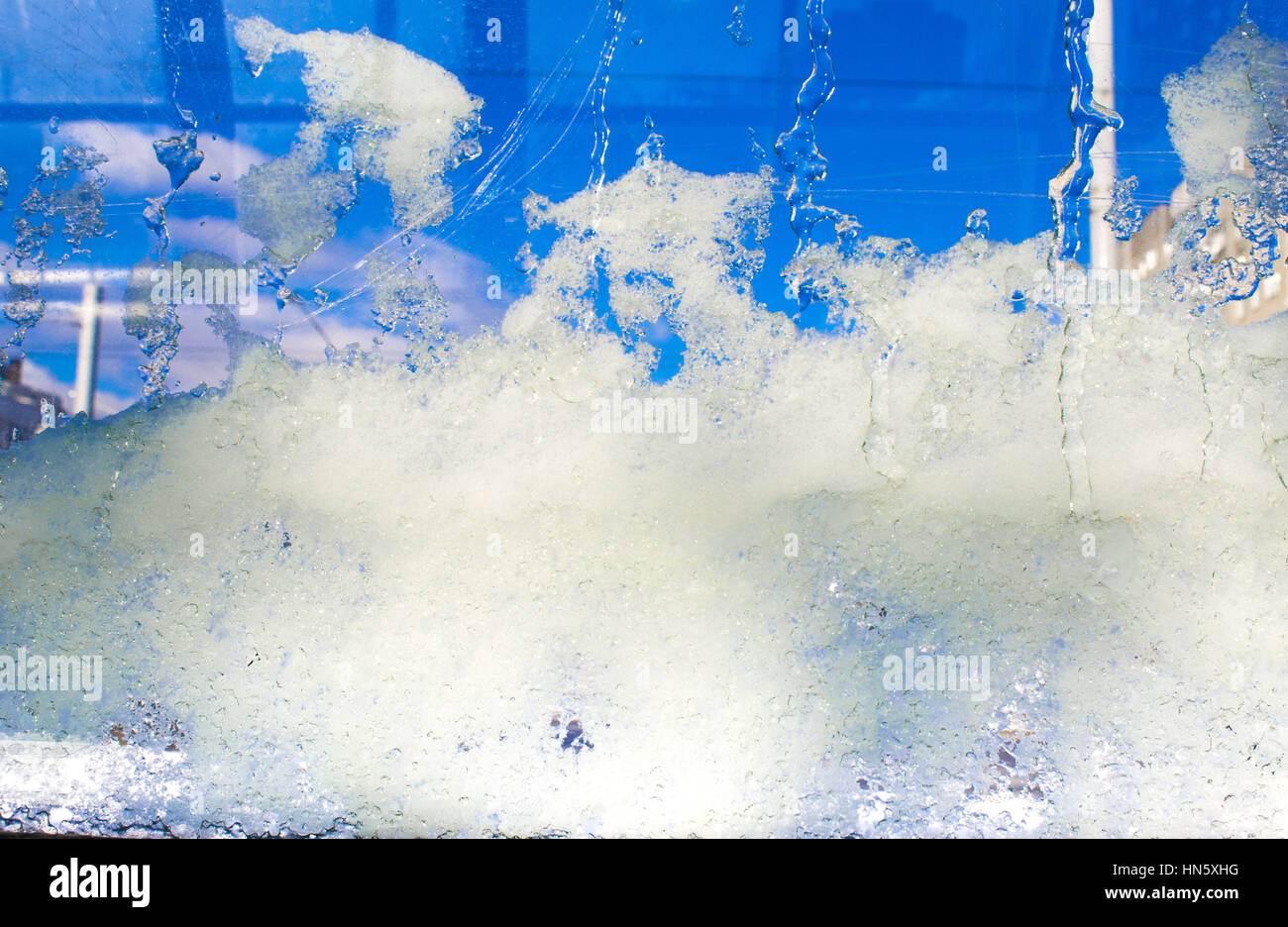 La glace bleue sur le verre, l'arrière-plan, la texture. Le gel de la neige sur le verre, verre transparent de la fenêtre en hiver et la fonte des glaces en contact avec chaud matin su Banque D'Images