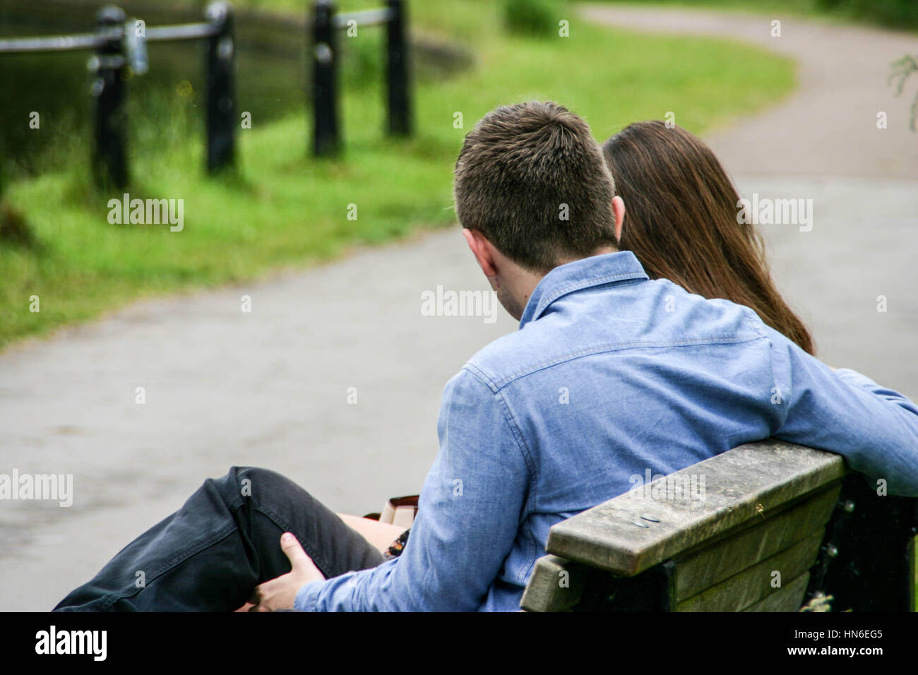 Jeune couple cuddling sur un banc de parc Banque D'Images