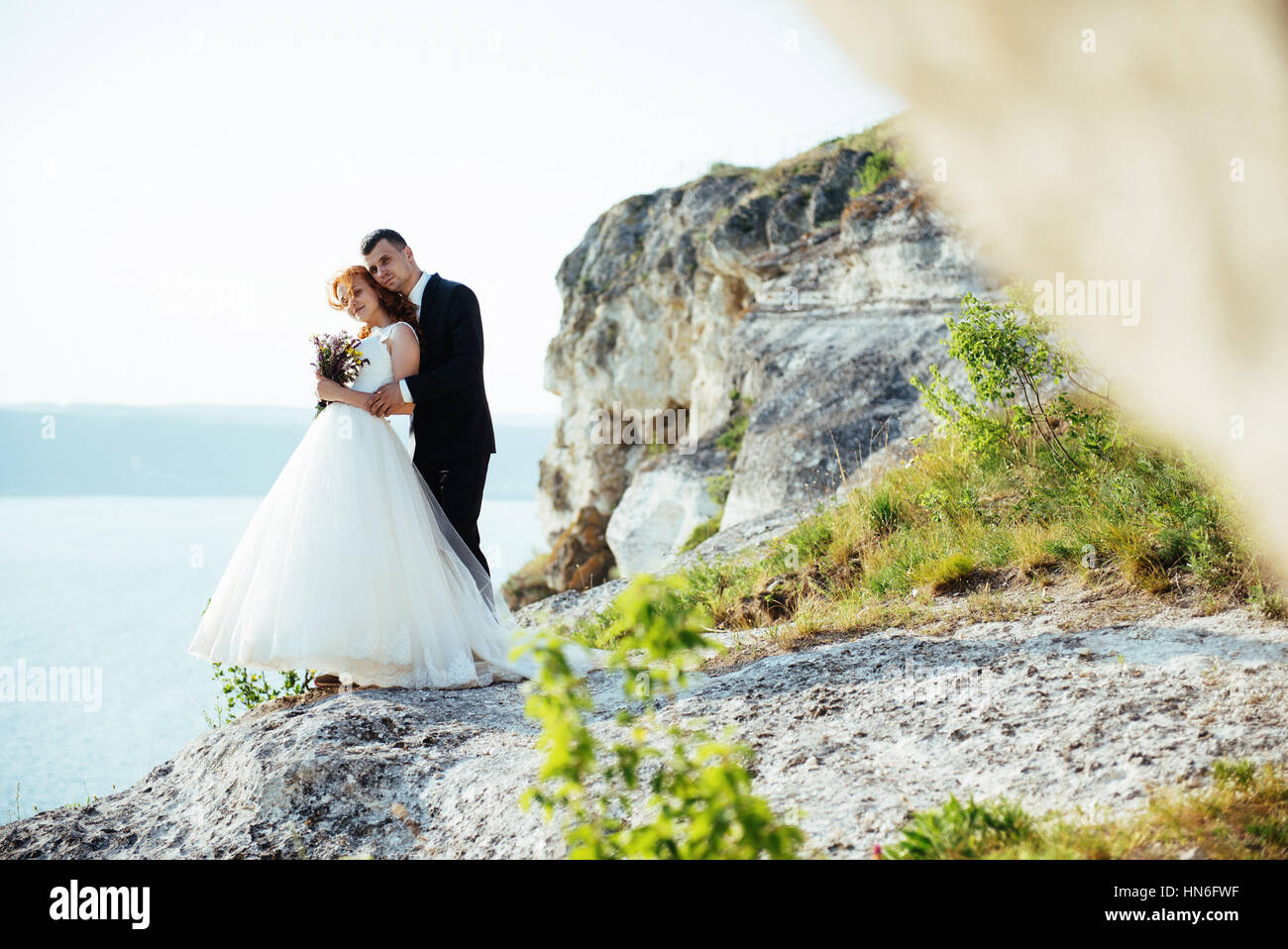 Gorgeous blonde Bride and Groom classy sur les rochers, au milieu de la se Banque D'Images