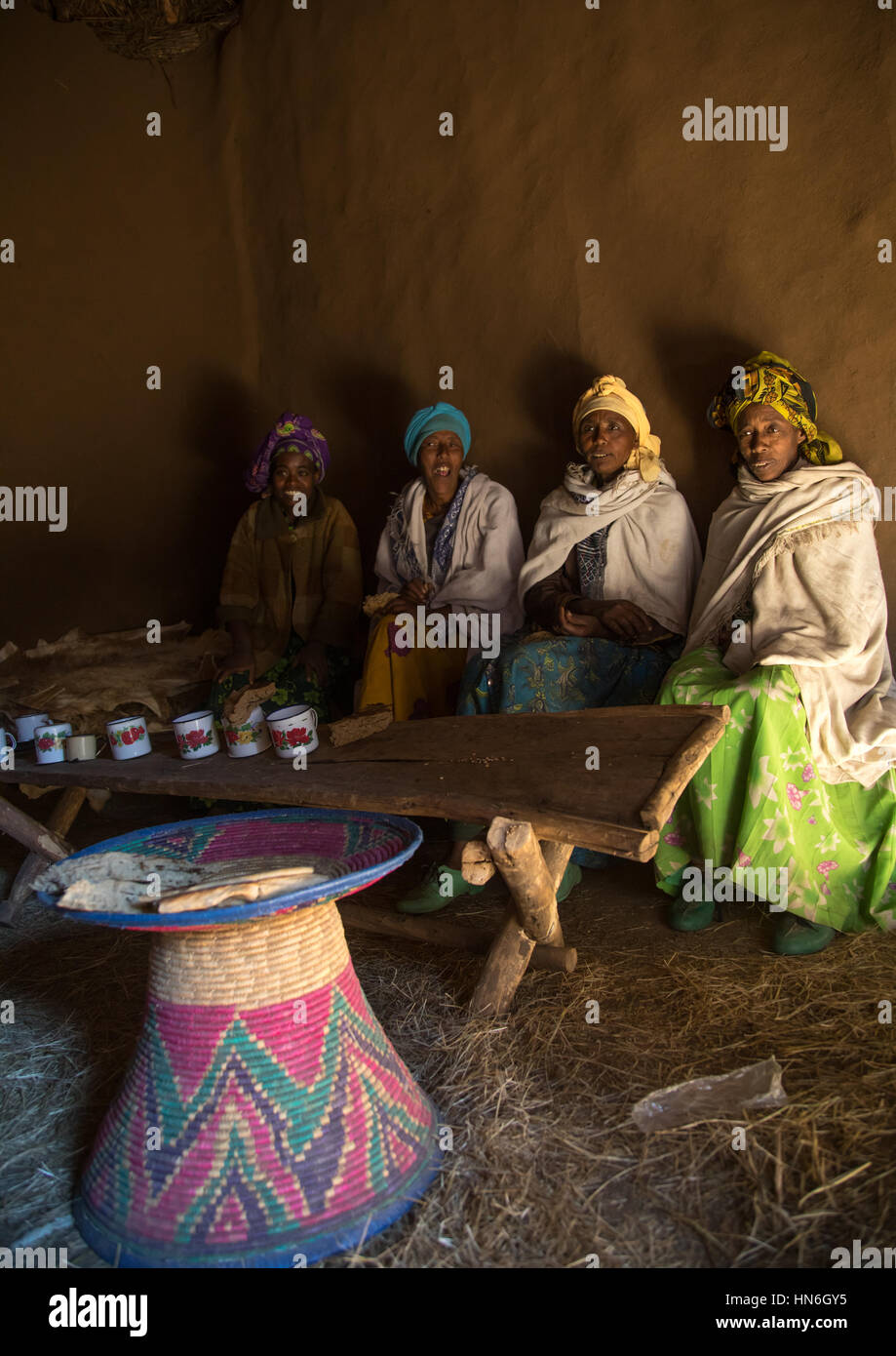 Les femmes éthiopiennes de la région des Highlands dans une maison à partager un verre et manger du pain, région d'Amhara, Debre Birhan, Ethiopie Banque D'Images
