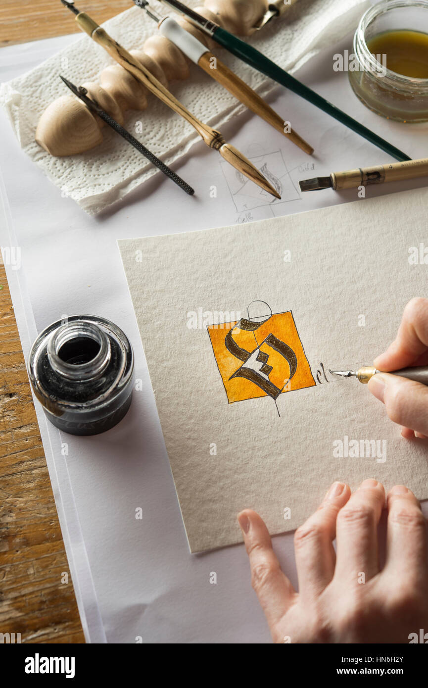 Studio de calligraphie, l'écriture de texte à la main avec un crayon et plume, lettre S de poudre d'or sur papier torchon Banque D'Images