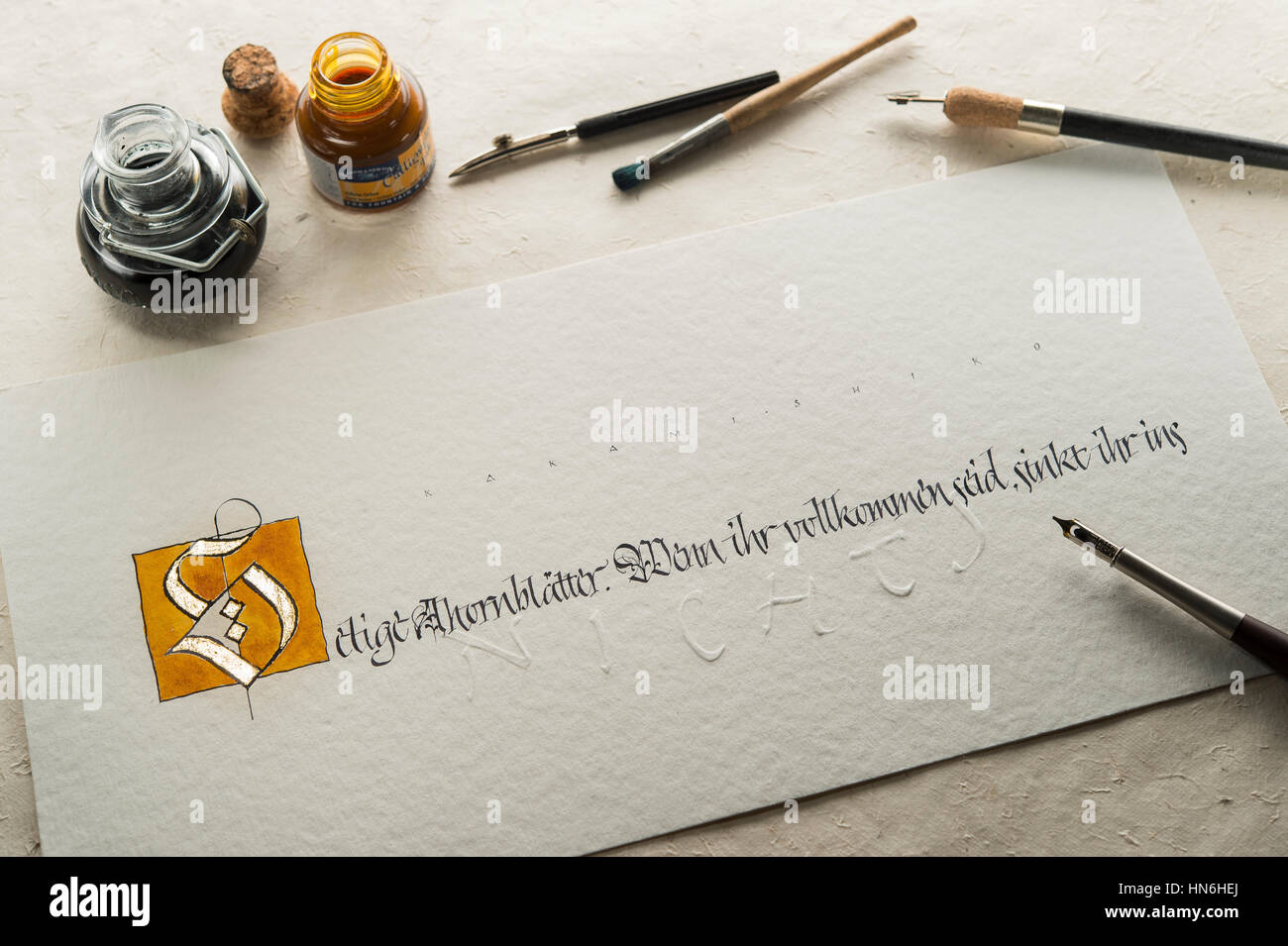 Studio de calligraphie, part écrit le texte avec un stylo et plume, lettre S de poudre d'or et de l'écrit sur papier torchon Banque D'Images