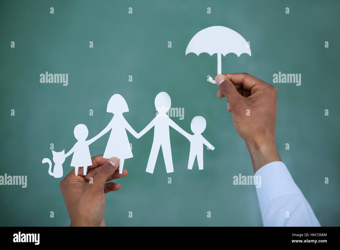 La protection de l'homme coupe papier avec la famille parapluie sur fond vert Banque D'Images