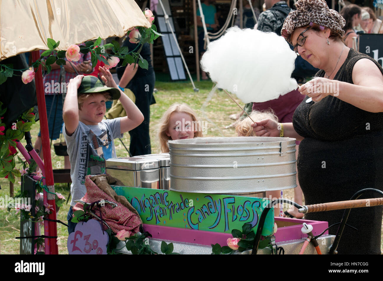 Deux enfants qui la regardent, en prévision d'une femme à faire de la barbe à papa au Port Eliot Cornwall Festival Banque D'Images