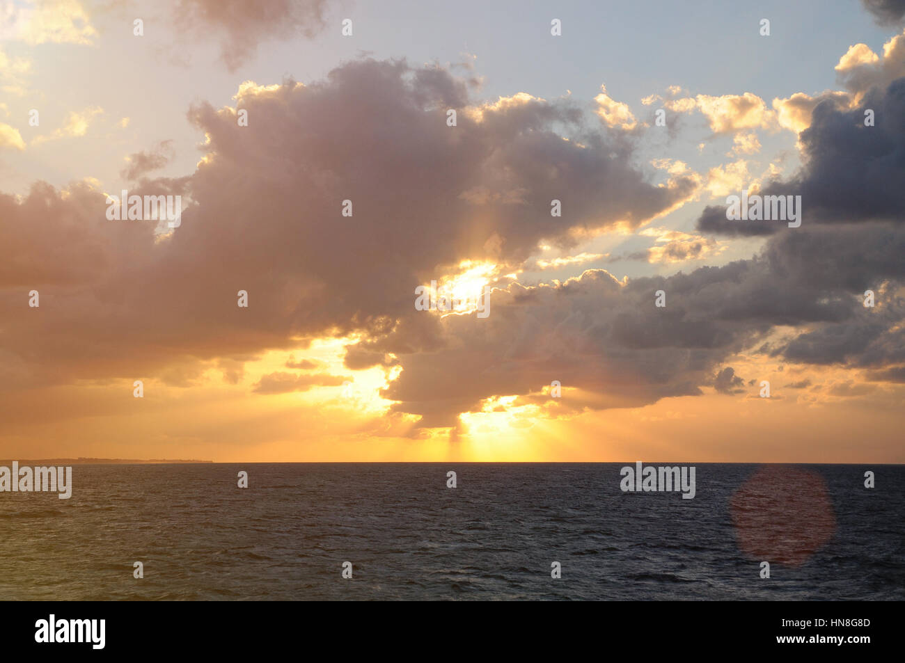 Lever du soleil en vertu de l'océan avec des rayons de soleil venant de nuages ciel Banque D'Images