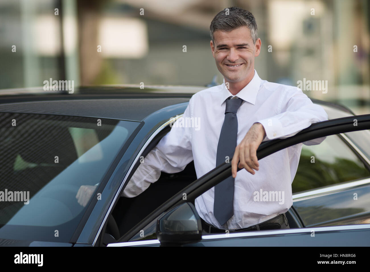 Businessman leaning on la porte de la voiture et smiling at camera, du concessionnaire, concept d'entreprise Banque D'Images