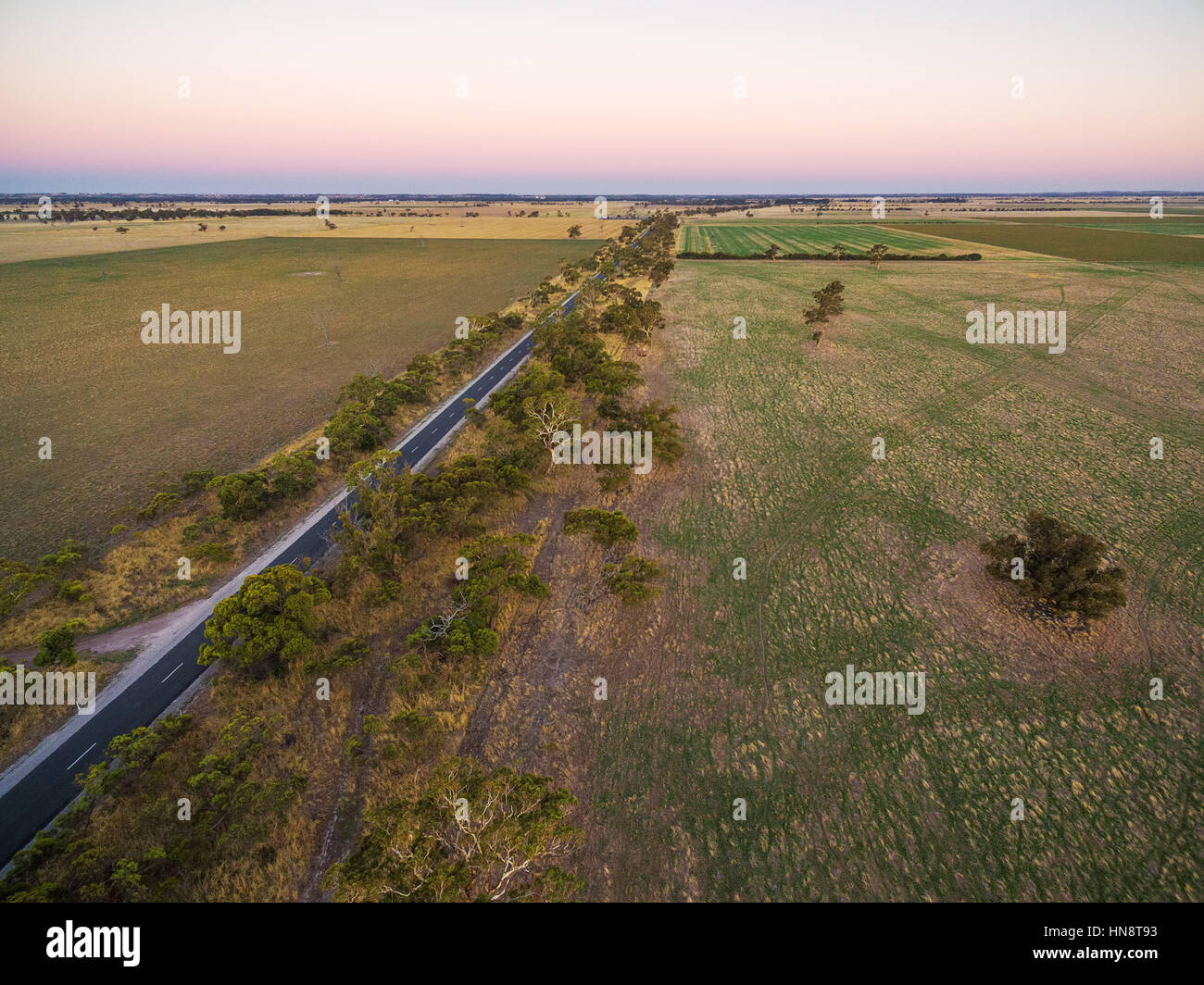 Les pâturages et prairies rurales en Australie au coucher du soleil Vue aérienne avec chemin rural traversant Banque D'Images