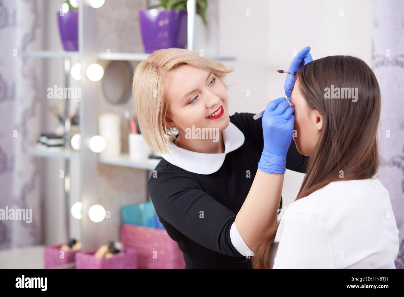 Cosmetologist professionnel gants à plumer des sourcils avec brosse et  pinces pour client dans un salon de beauté. Femme blonde en maquillage  permanent pour Photo Stock - Alamy