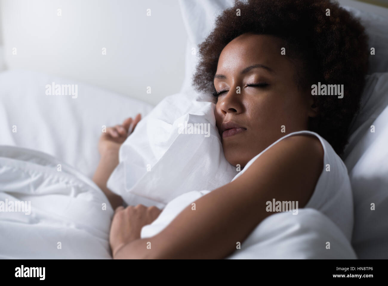 Jeune femme africaine de dormir dans son lit la nuit, elle se repose avec les yeux fermé Banque D'Images