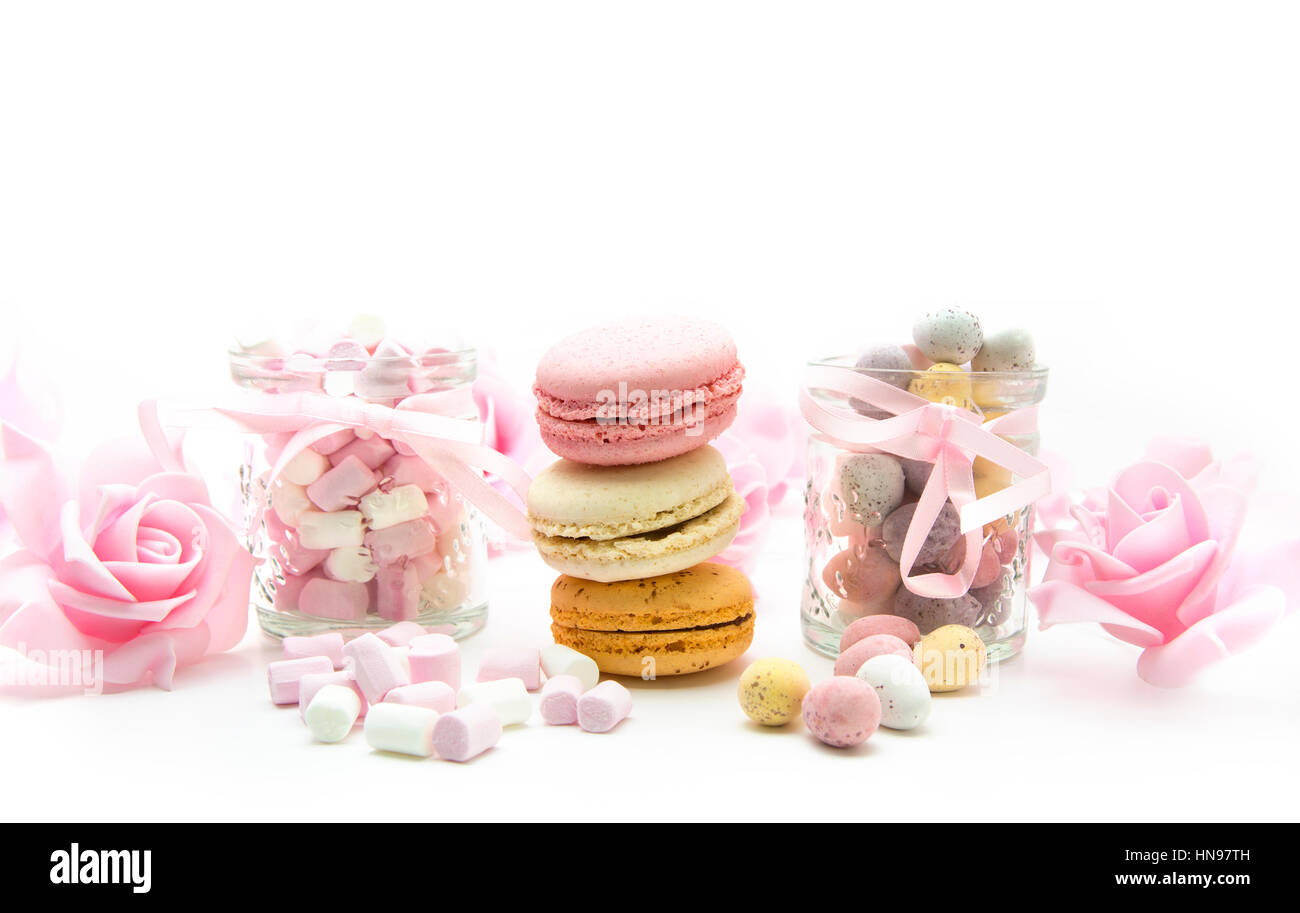 Les œufs de pâques avec traite, marhmallows, macarons et roses sur fond blanc Banque D'Images