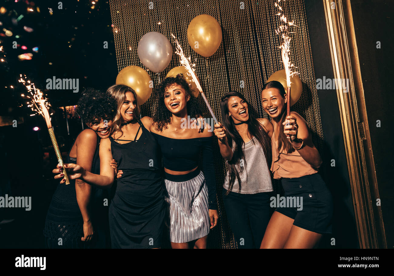 Groupe de femmes célébrant avec Fireworks at pub. Female friends enjoying party at nightclub. Banque D'Images