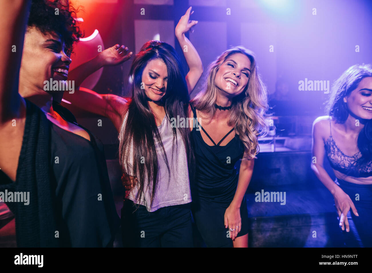 Photo de heureux les jeunes de s'amuser à la discothèque. Amies danser ensemble dans une boîte de nuit. Banque D'Images