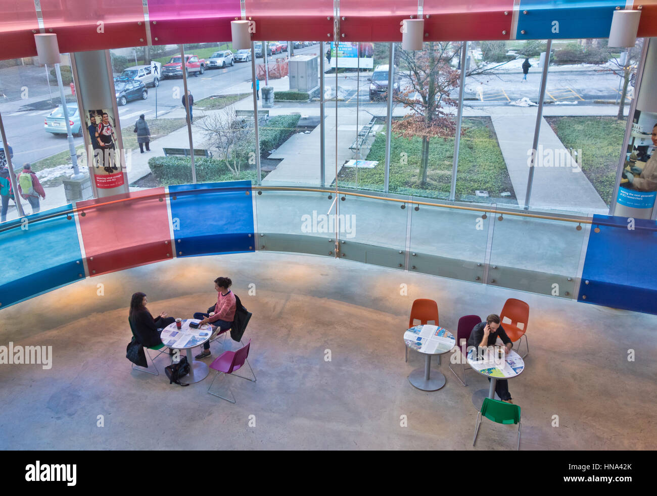 Les gens assis à des petites tables rondes dans l'atrium de l'Blusson spinal cord Centre à Vancouver Banque D'Images