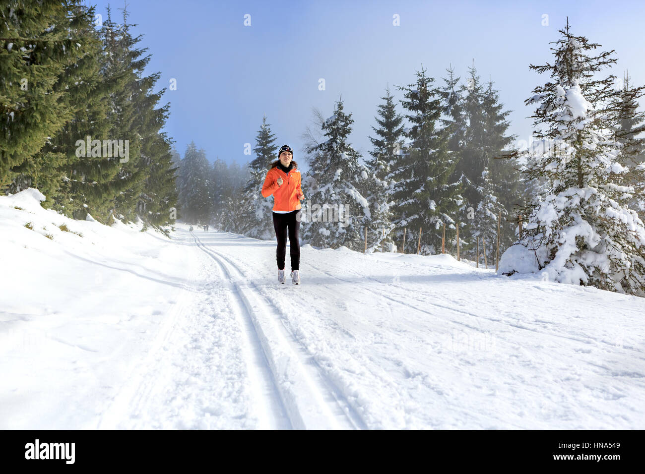 Une jeune femme le jogging dans la forêt d'hiver Banque D'Images