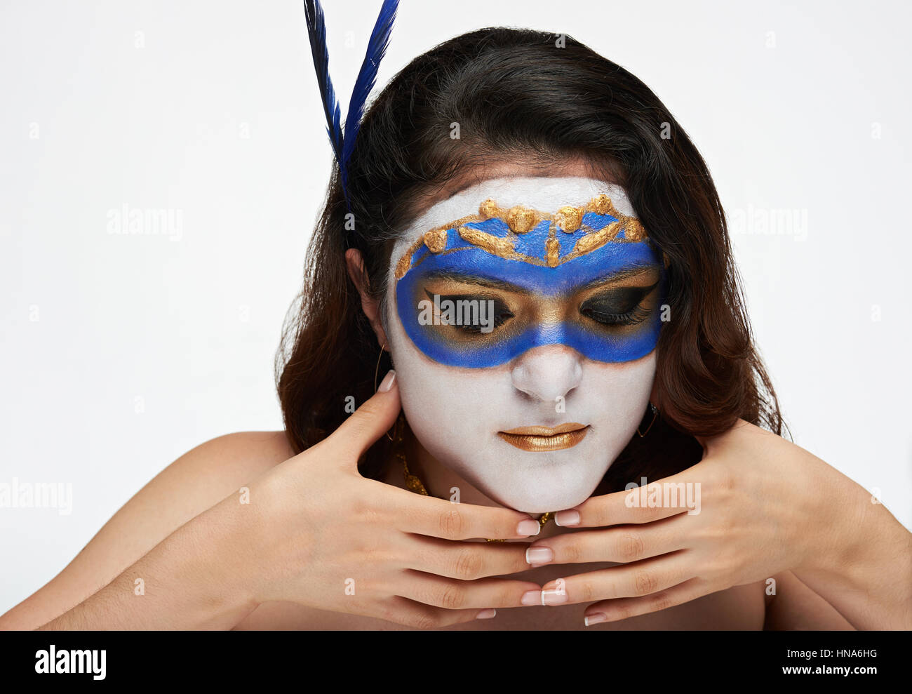 Les femmes détiennent masque d'or sur la face blanche isolée Banque D'Images