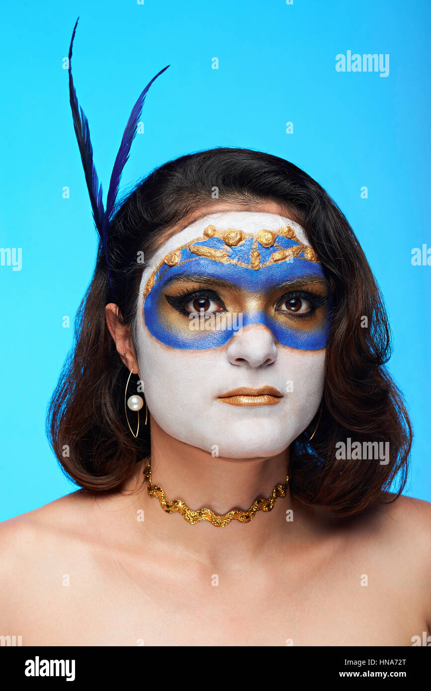 Portrait de femme sérieuse avec masque body art sur fond bleu Banque D'Images